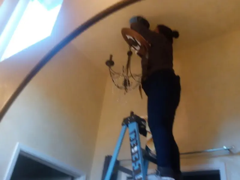 Electrician installing a chandelier in a Lee's Summit residence